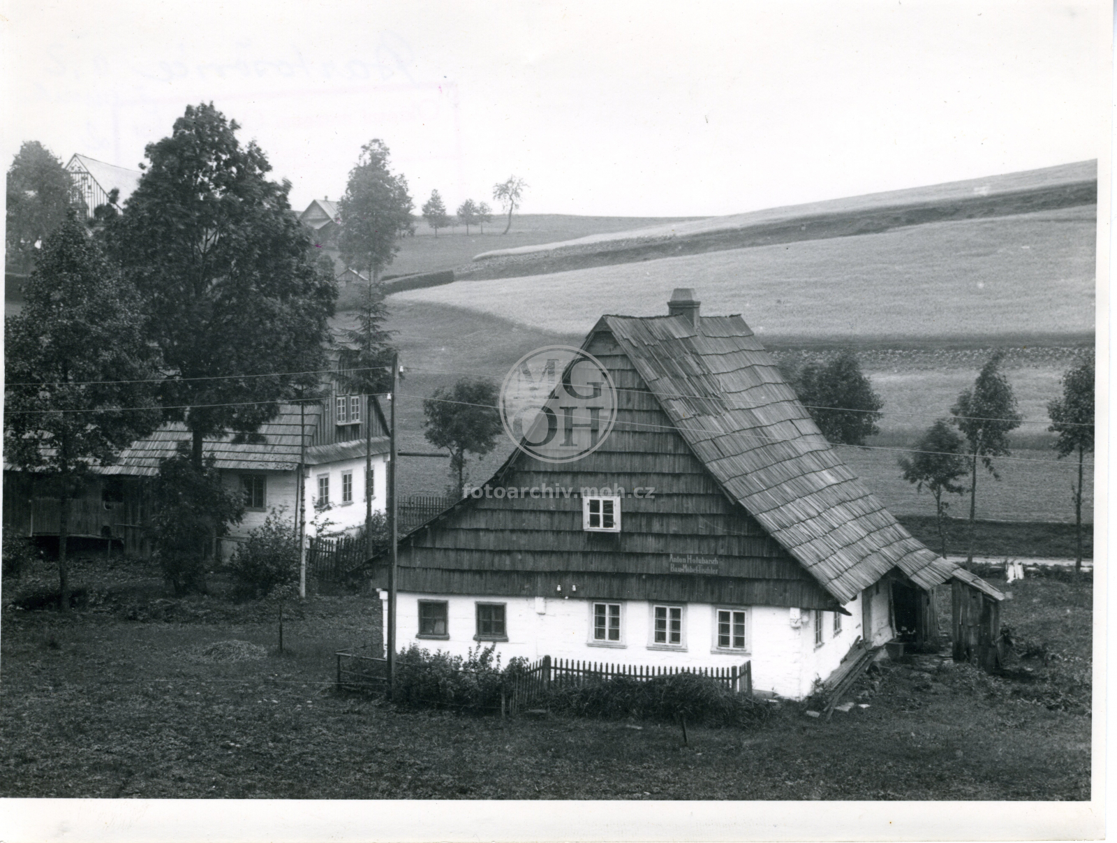 Fotografie - Roubená lidová stavba obílená, krytá šindelem i na štítu. Horský typ. Vývěsný štít: Anton Holubarsch Bau-Möbel-Tischler