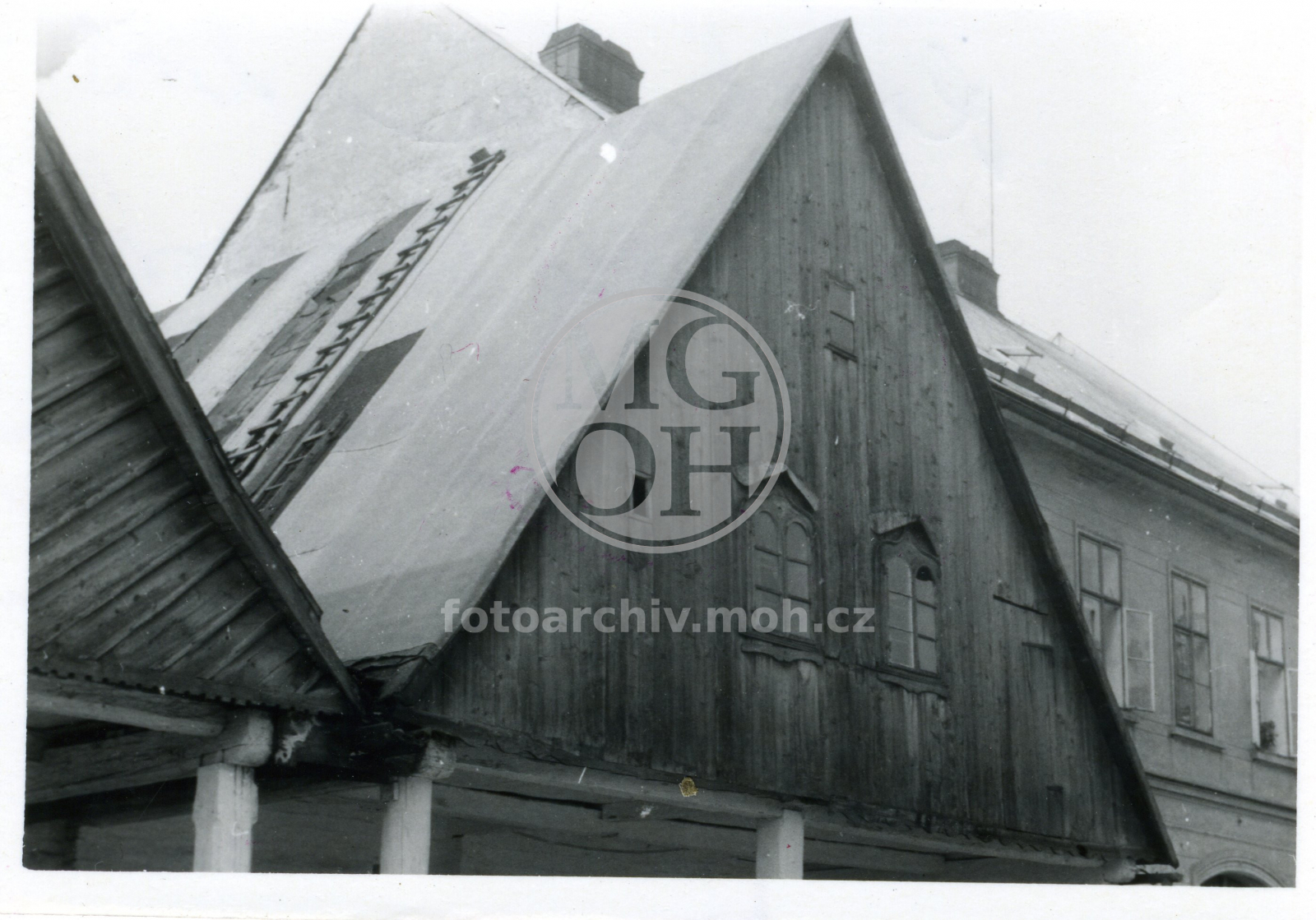 Fotografie - Štíty dřevěných chalup, v pozadí zděná stavba