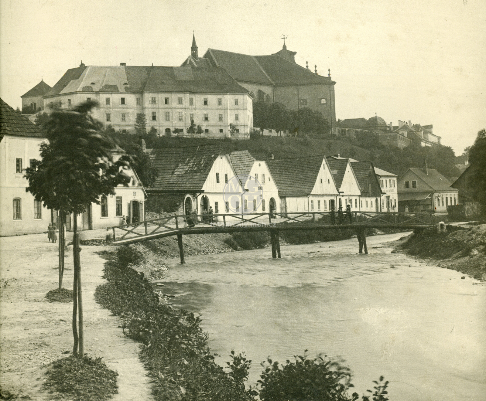 Fotografie - Nové domy, dřevěný most pod piaristickým gymnasiem, kostel Nejsvětější Trojice