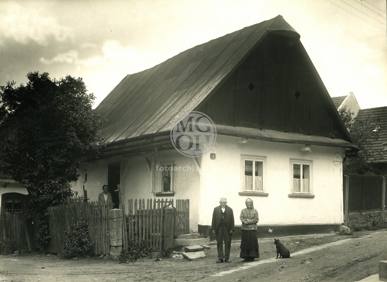 Fotografie - Potštejnská ulice, dům čp. 12 [na domku čp. 10], u Trkalů, zbořen 1931
Před domem Filip Trkal s manželkou, ve dveřích stojí slečna Minaříková. 